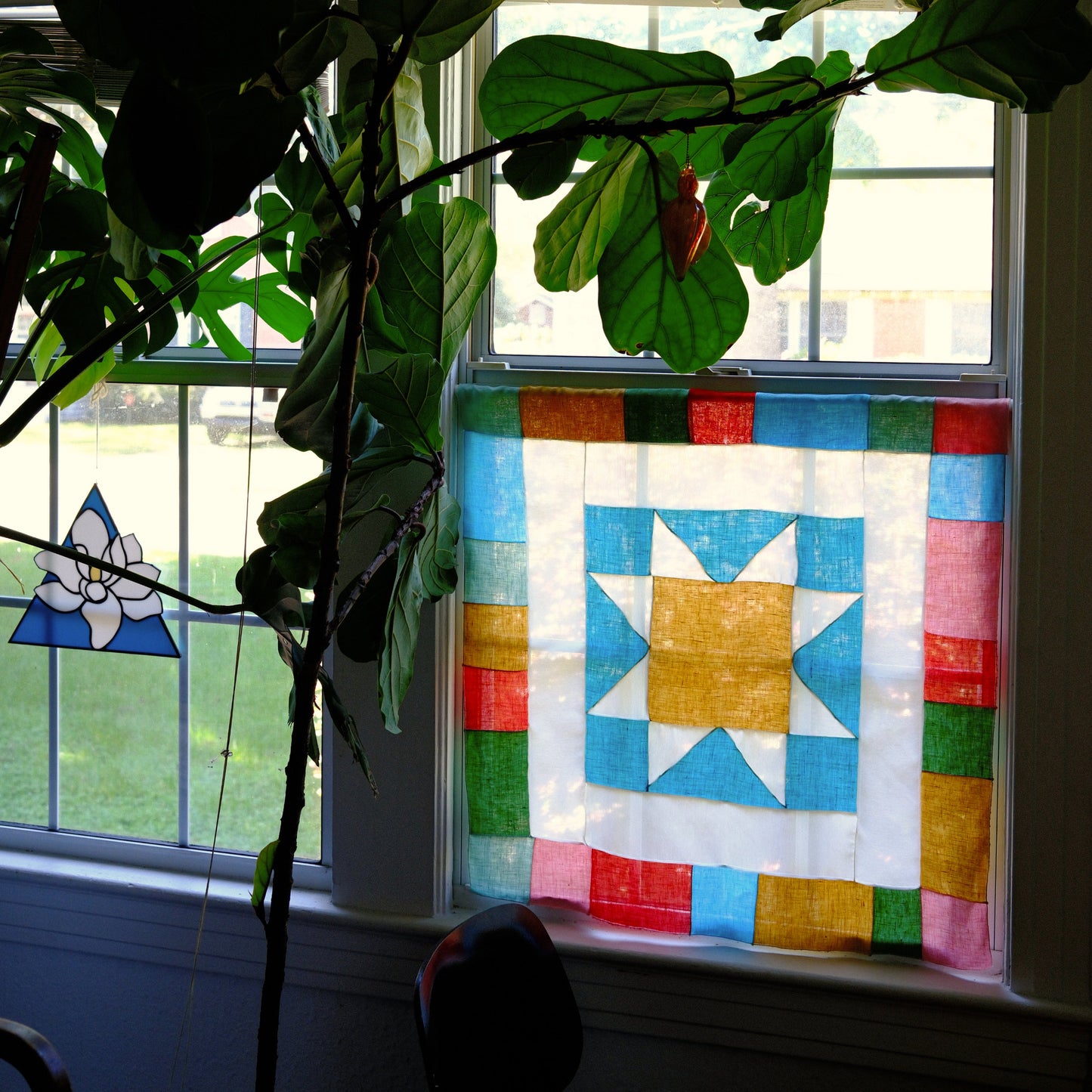 Colorful quilt with star pattern on a window sill next to a plant
