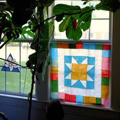 Colorful quilt with star pattern on a window sill next to a plant