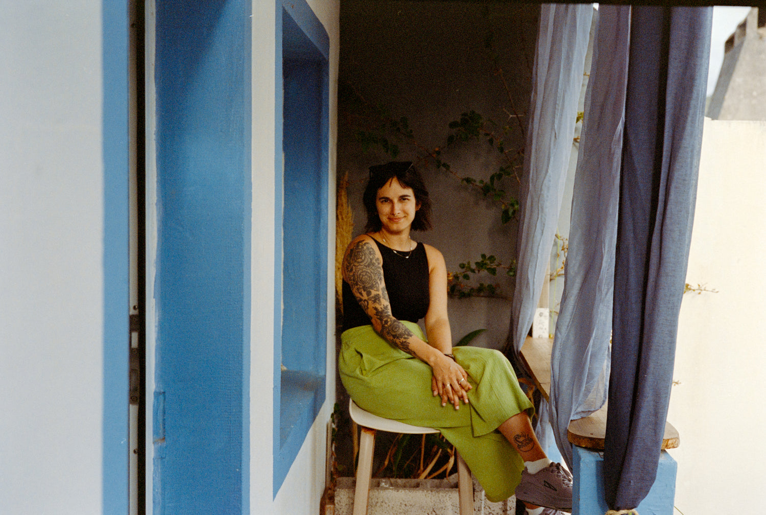 Woman sitting on a chair in a room with blue walls and a curtain.